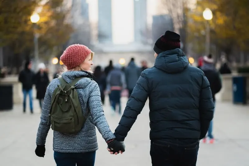man and woman holding hands while walking in the street