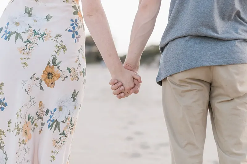 man and woman holding hands on sand field