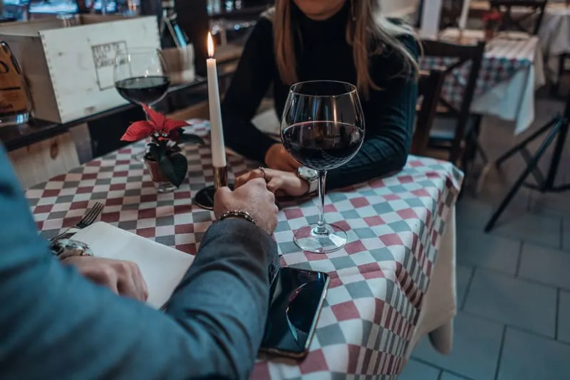 man and woman holding across the table with glasses of wine on it