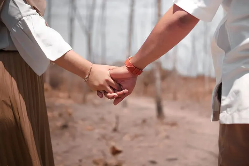 man and woman holding hands in the wood during daytime
