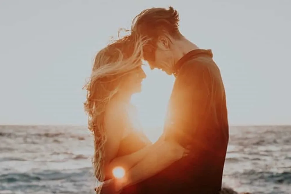 man and woman hugging near sea during golden hour