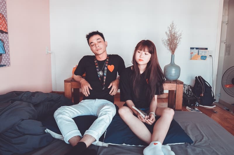 man and woman in black shirts sits in the bed