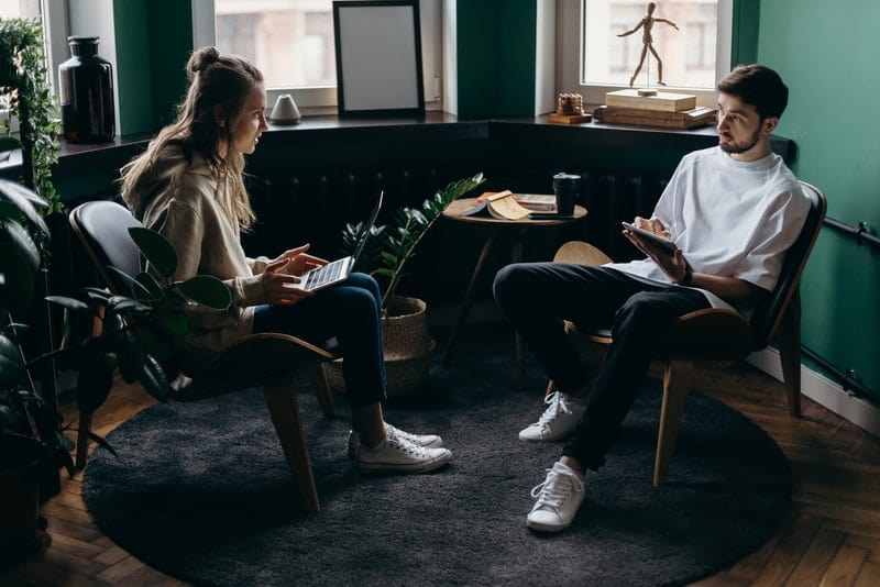 man and woman on gadgets sitting inside a room