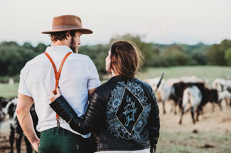 uomo e donna su un campo verde con bestiame durante il giorno