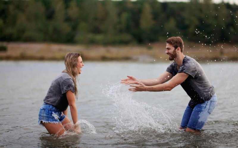 Uomo e donna che giocano in uno specchio d'acqua durante il giorno