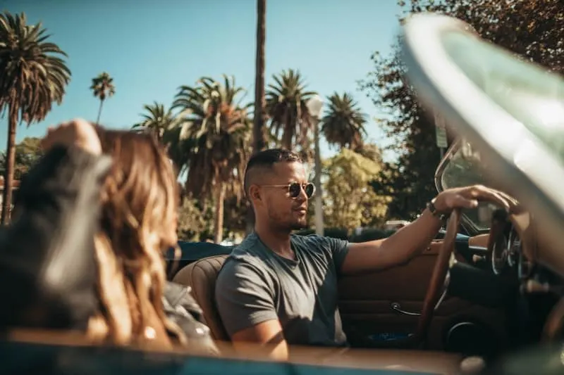 man and woman riding on a convertible car