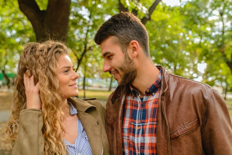 man and woman seeing eye to eye wearing brown leather jackets located in the park