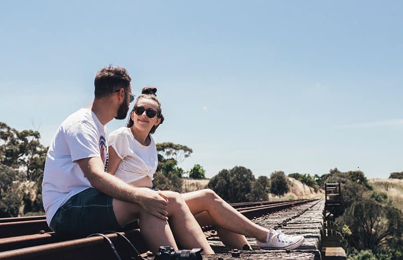 uomo e donna seduti lungo la ferrovia