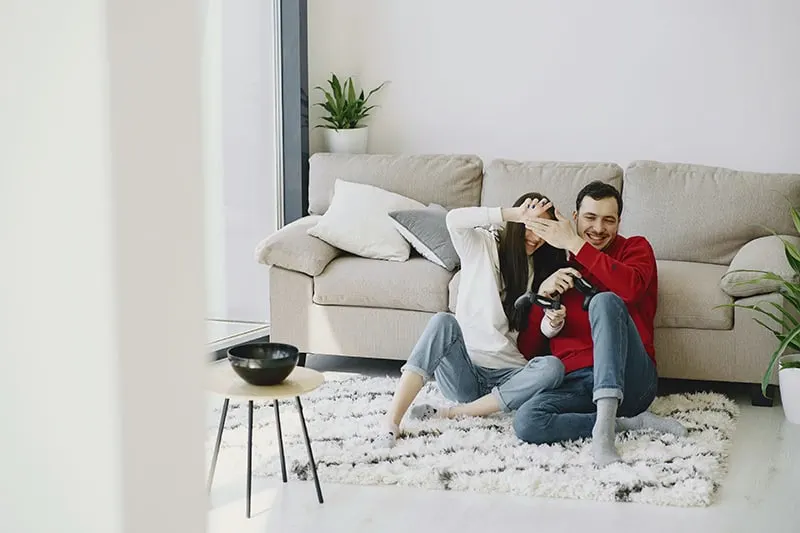 man and woman sitting on carpet while laughing