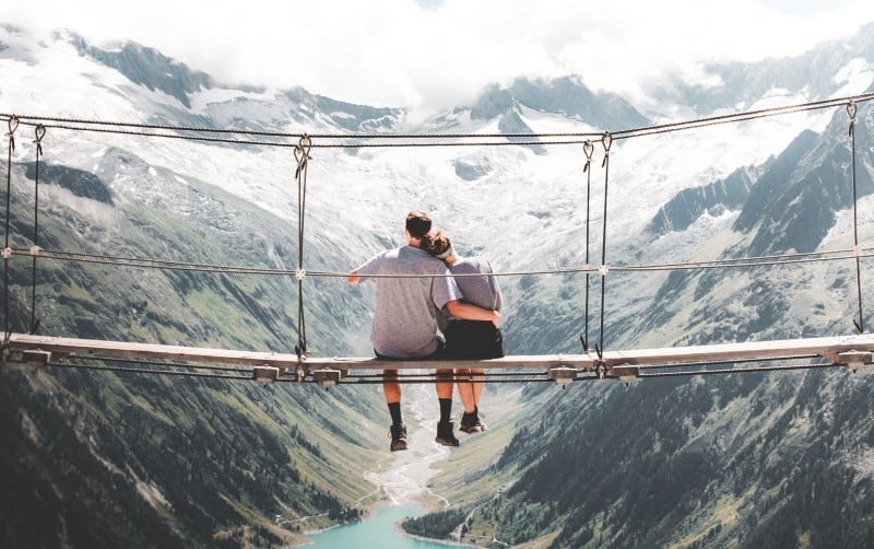 Man and woman sitting on hanging bridge at daytime