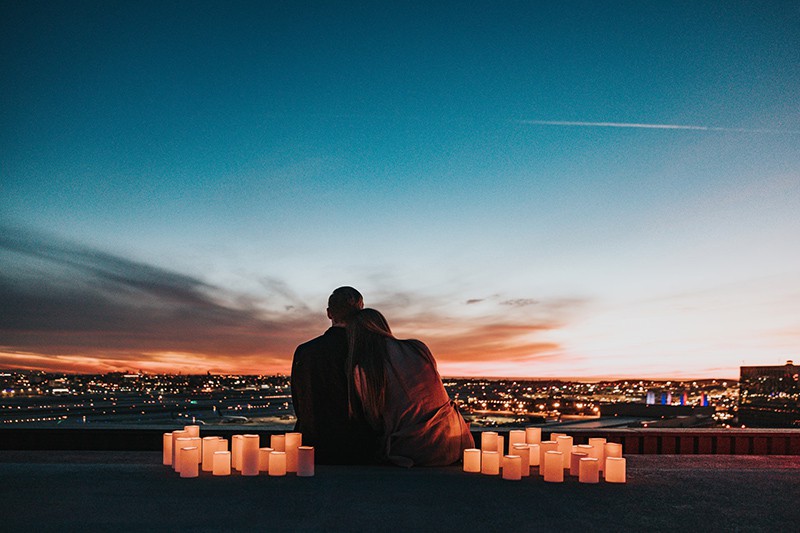 uomo e donna seduti a terra di fronte alla città