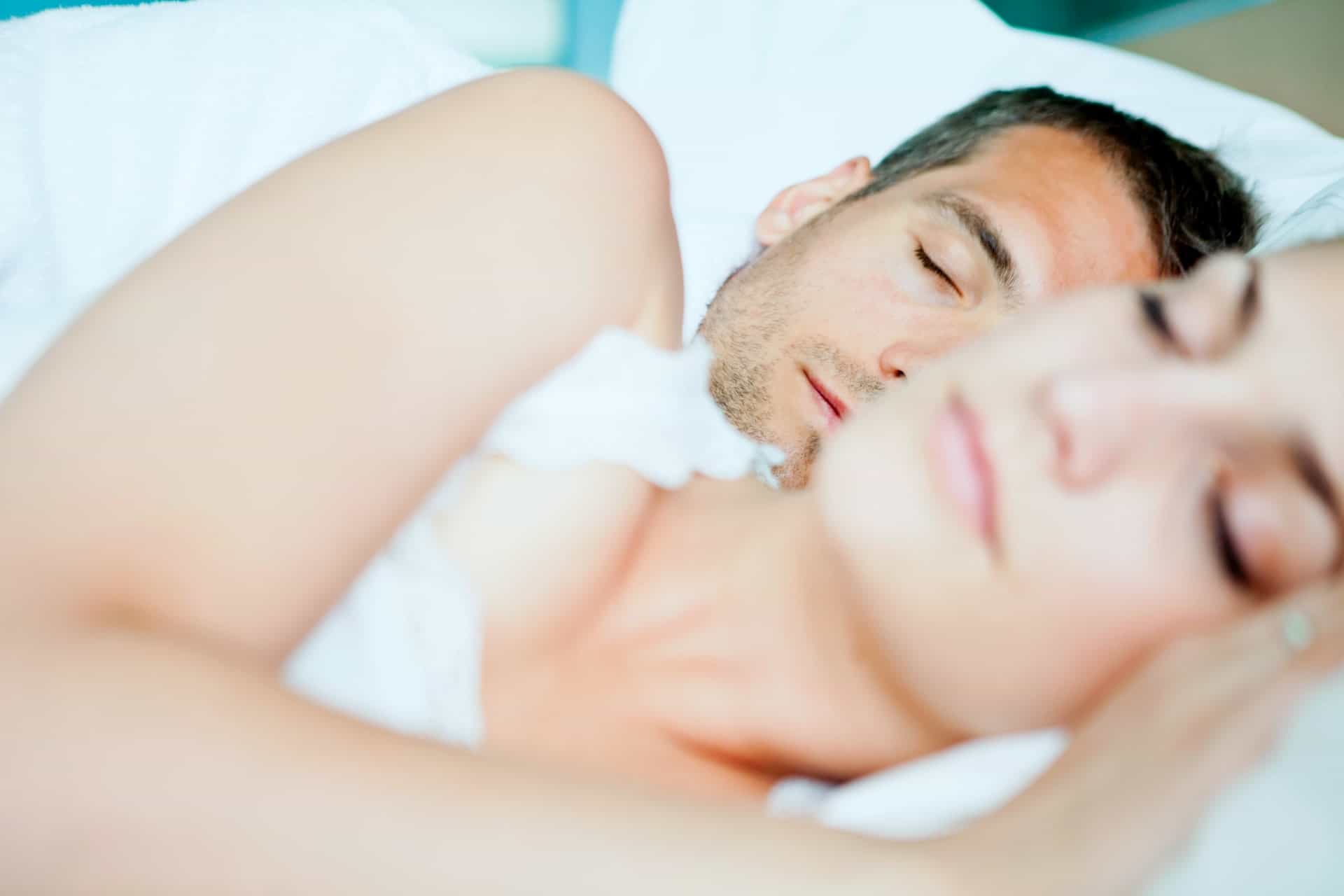 man and woman sleeping in bed with white sheets