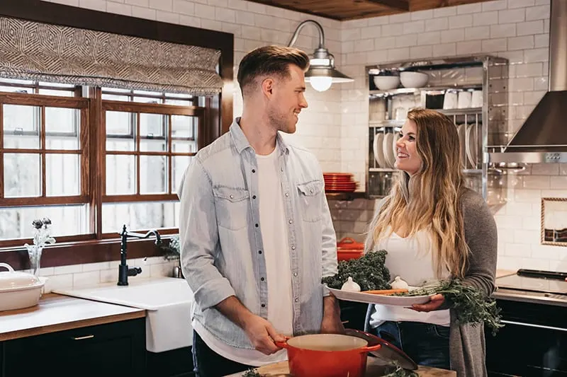 man and woman standing inside kitchen while preparing food