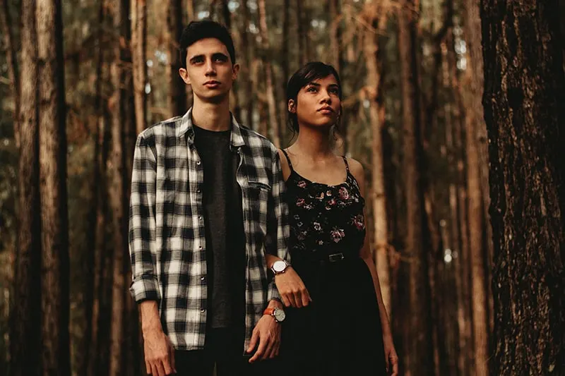 man and woman standing next to another in forest