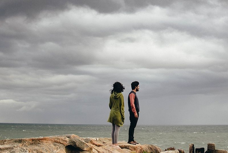 uomo e donna in piedi su una scogliera vicino al mare