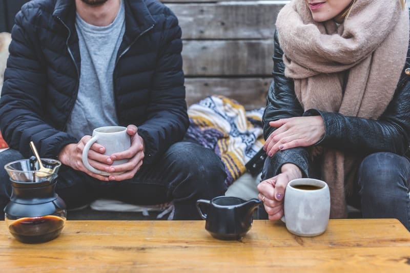 uomo e donna che parlano tenendo in mano un caffè in abiti invernali