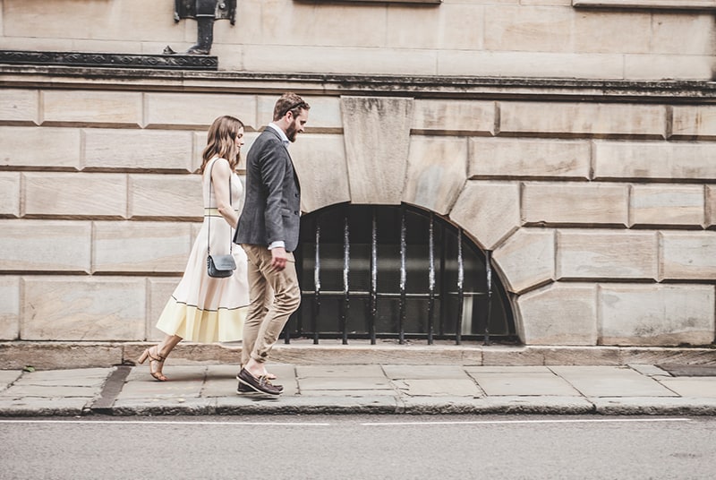 uomo e donna che camminano lungo una strada durante il giorno