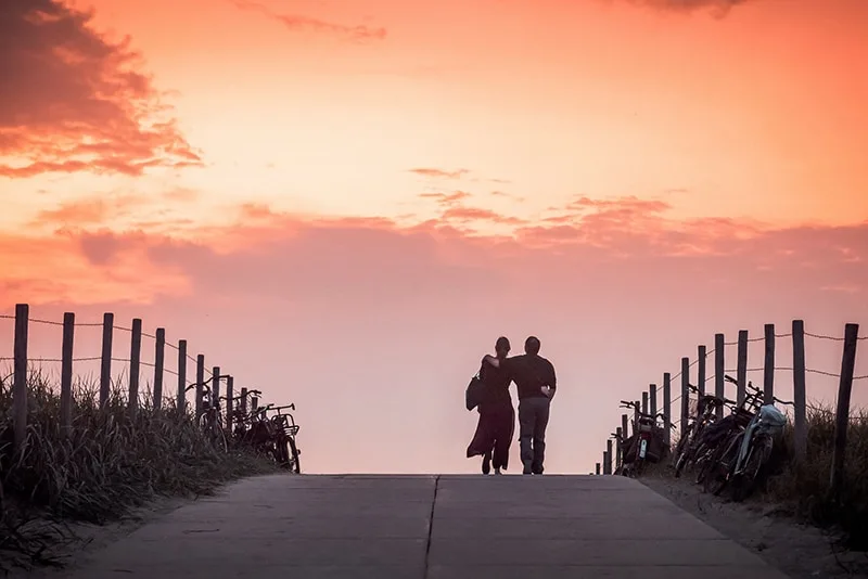 man and woman walking on road during dawn