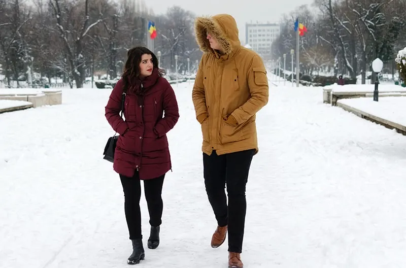 man and woman walking on the snow during daytime