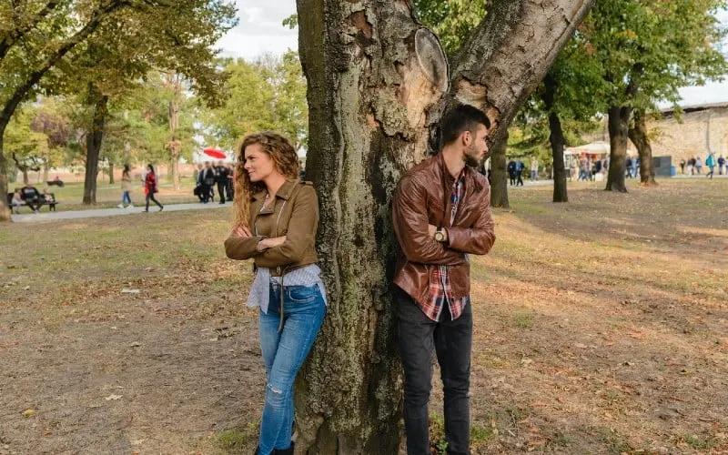 man and woman wearing leather jackets standing under tree
