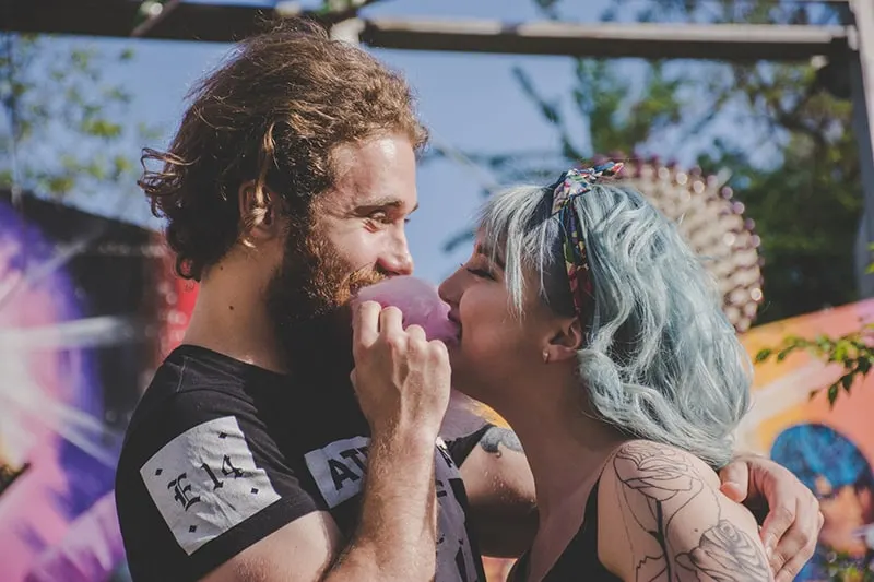 man and woman with blue hair smiling and eating cotton candy