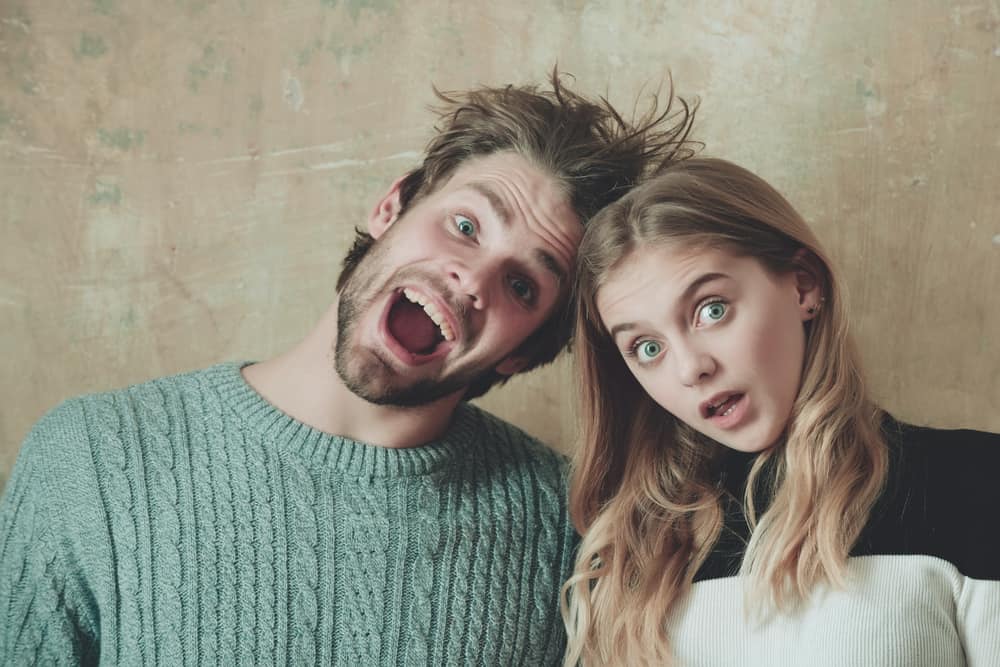 Man and woman with their mouth opened standing against wall