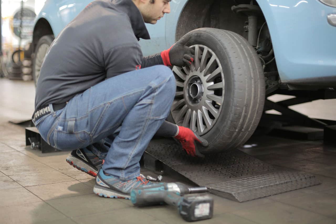 man changing tire wearing gray long sleeves and gloves