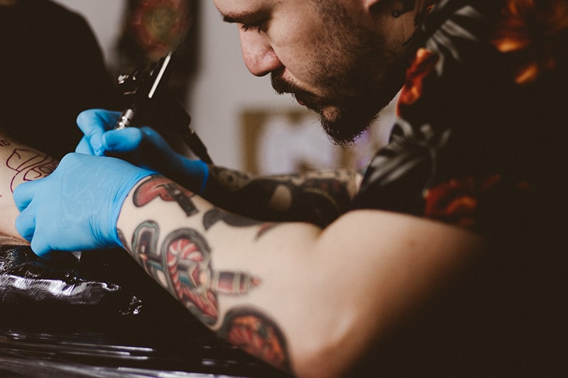 hombre haciendo tatuaje en el brazo de una persona