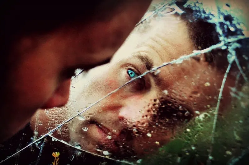 man facing broken mirror on focus on his blue eye