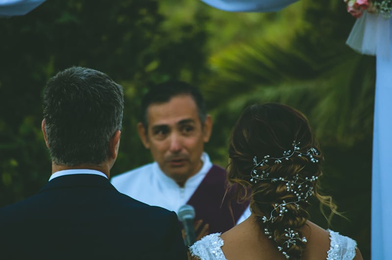 man holding a microphone in front of wedding couple