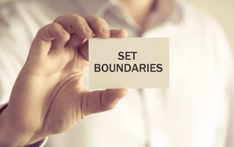 Hamd of a man holding a set boundaries card