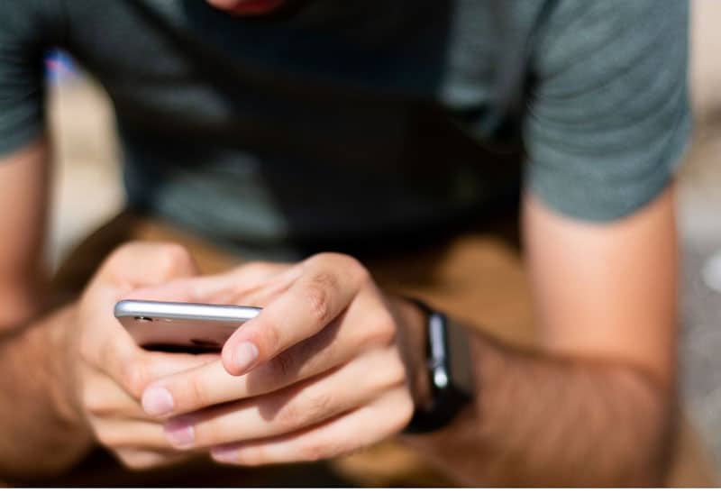 man holding cellphone with both hands wearing wristwatch on one wrist