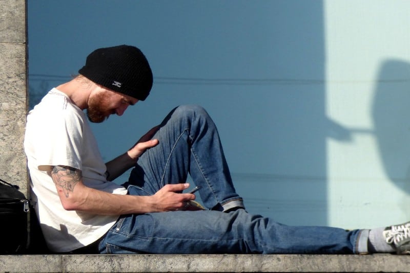 homem com boné preto a utilizar um smartphone