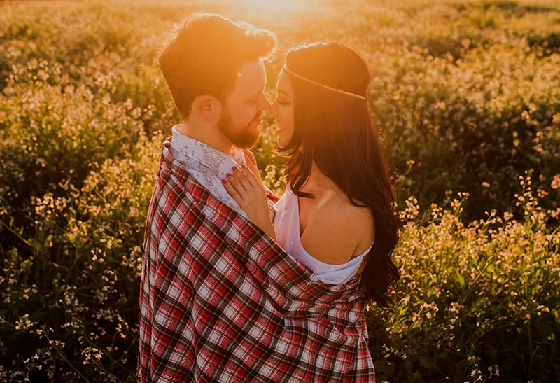 uomo che abbraccia una donna nel campo durante il tramonto