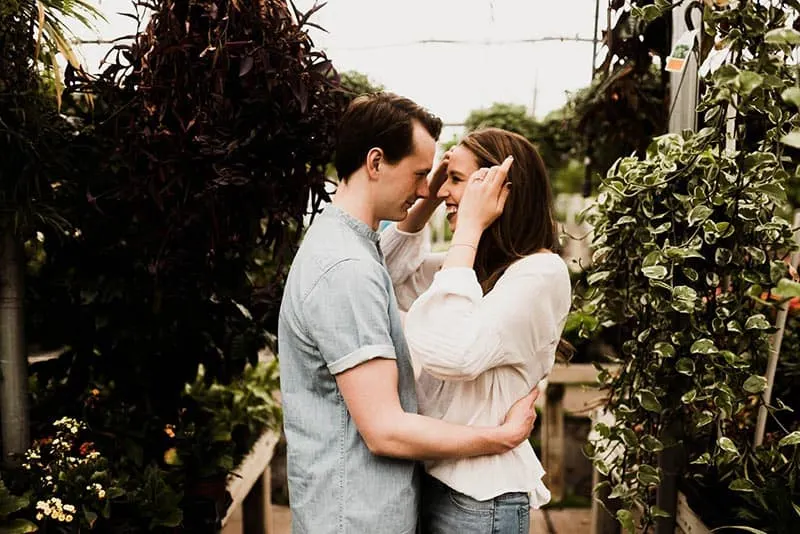 Man and woman hugging surrounded by plants