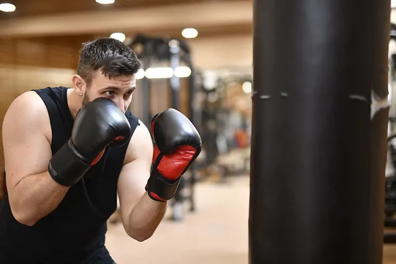 man in black tank top wearing boxing gloves