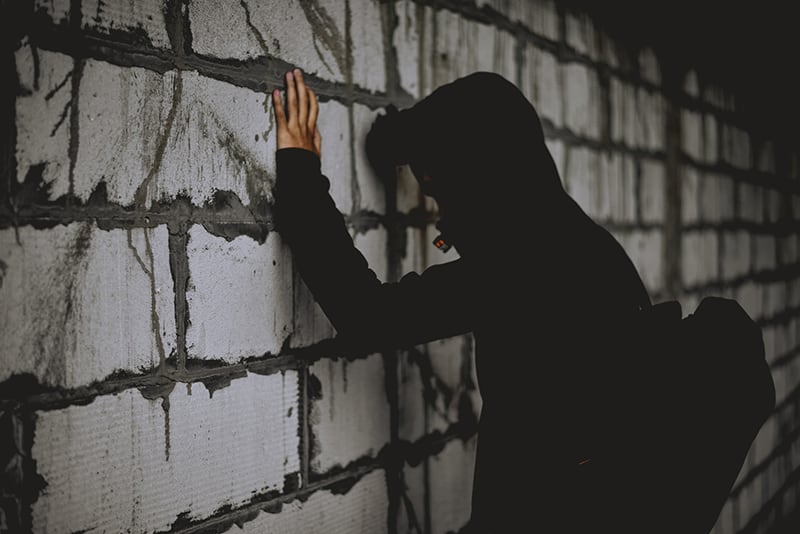 man in black leaning on wall