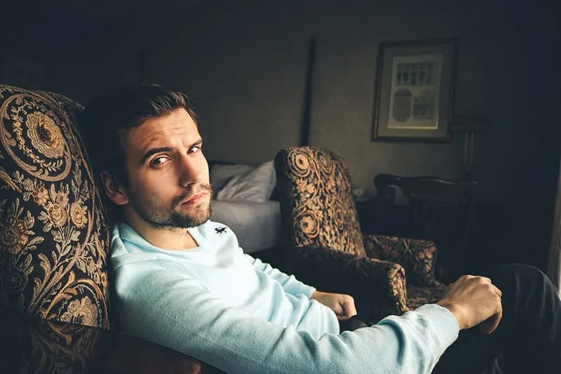 man in blue sweater sitting on the armchair