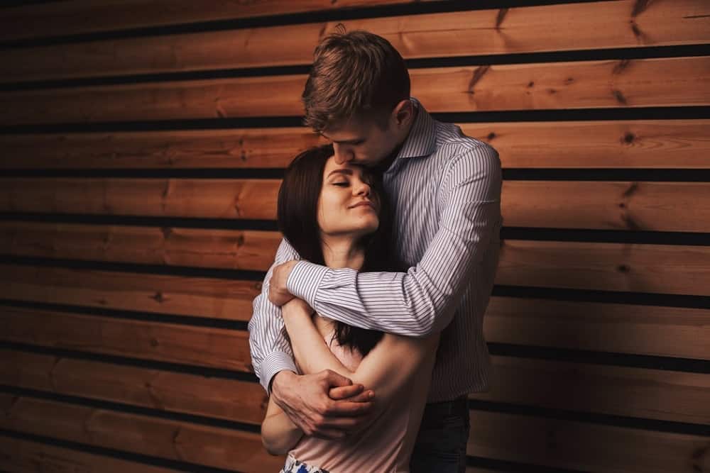 uomo con camicia a maniche lunghe a righe bianche e grigie che abbraccia una donna