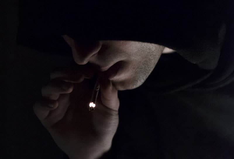 man in hoodie smoking cigarrette