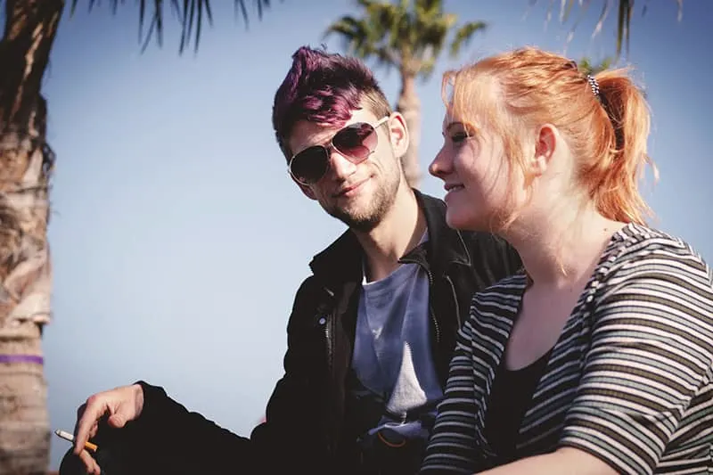 man in shades staring at a smiling woman beside him
