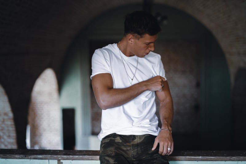 man sitting on stair and holding white shirt