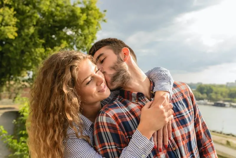 man kissing smiling woman outdoor