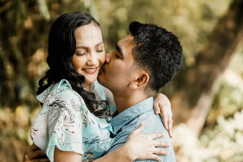 man kissing woman in blue floral dress on cheek