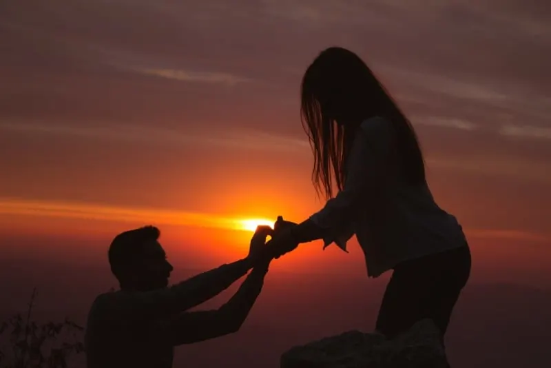 man kneeling in front of woman during sunset