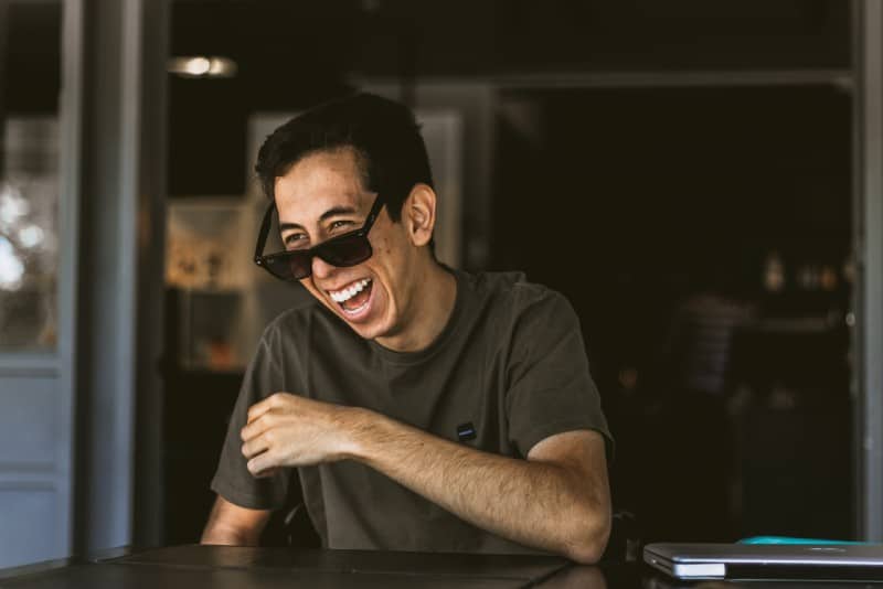 man wearing black sunglasses and laughing