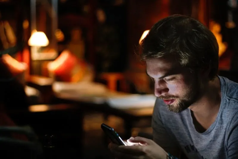 man sitting indoor and looking at phone