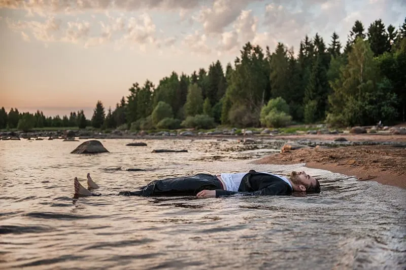 man lying in the river during the sunset