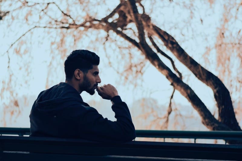 man in black hoodie sitting on bench