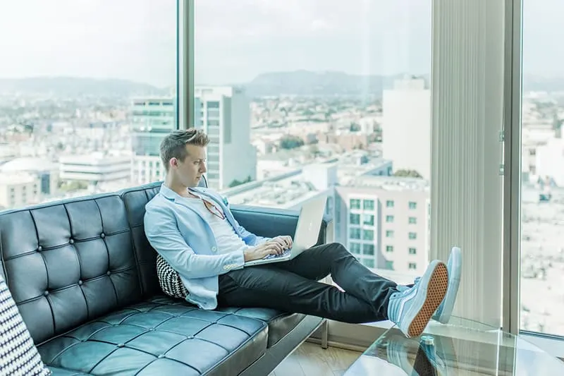 man sitting on the sofa using the laptop